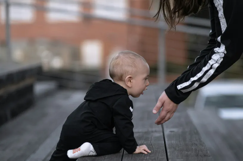 Vaakakuvassa portaita kiipeävä vauva potkupuvussa