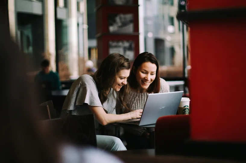 Two people are sitting at a computer.