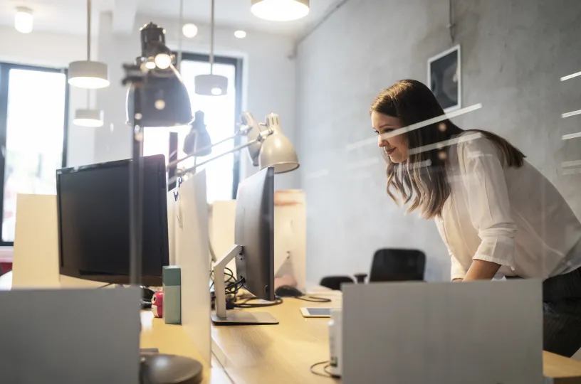 Nainen työskentelee modernissa avotoimistossa tietokoneen äärellä.