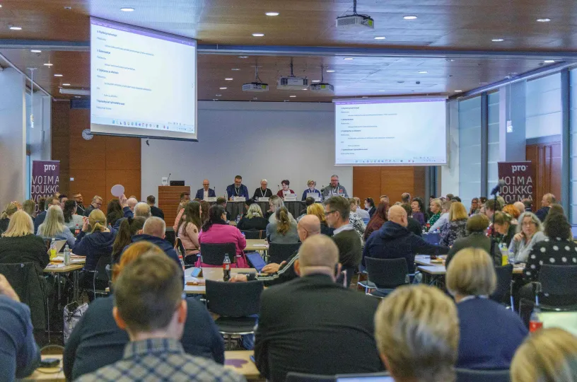 Iso kokoushuone täynnä ihmisiä.