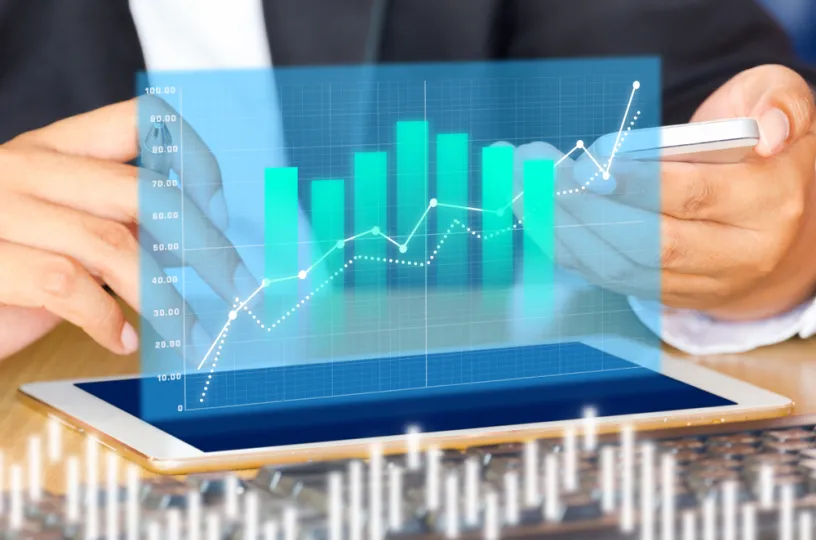 Henkilö katsoo talouslukuja tabletilta. 