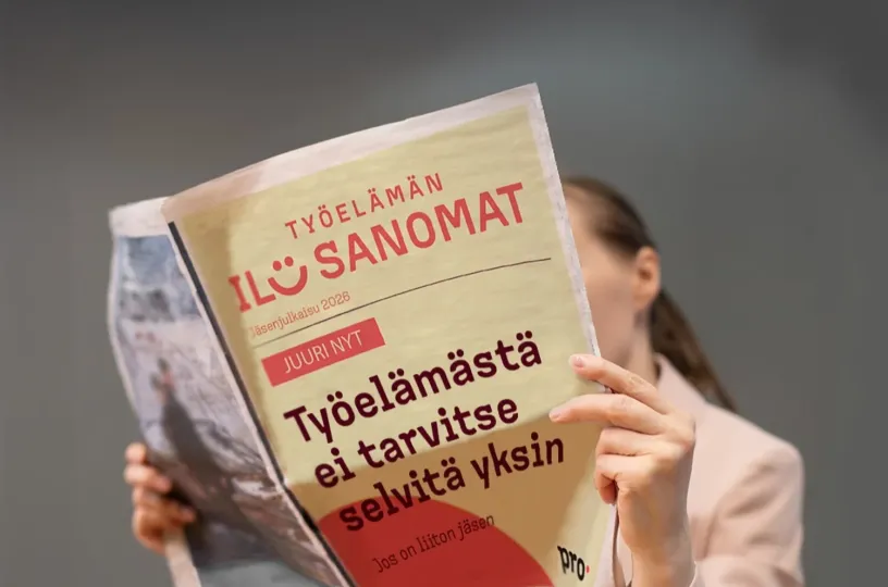 Henkilö lukee sanomalehteä, jonka kannessa punainen ja keltainen väritys.