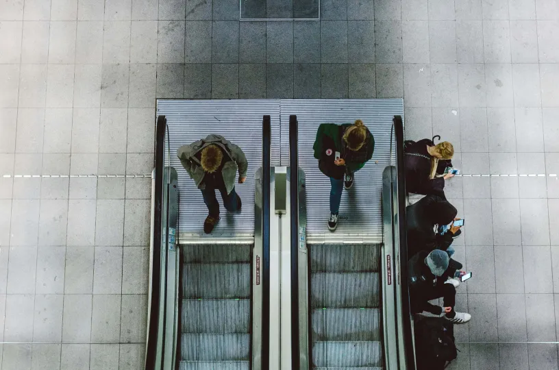 Kuvassa ihmisiä työmatkalla nousemassa rullaportaisiin.