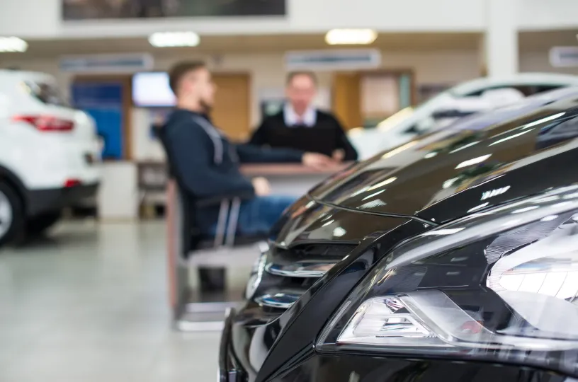 Autokauppa, autoliike, taustalla ihmisiä
