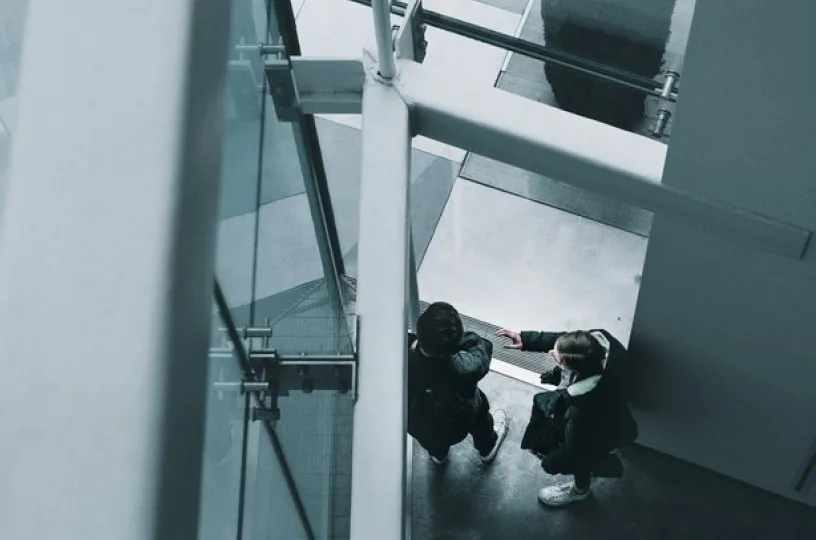 Kaksi ihmistä kättelee modernin rakennuksen sisällä.