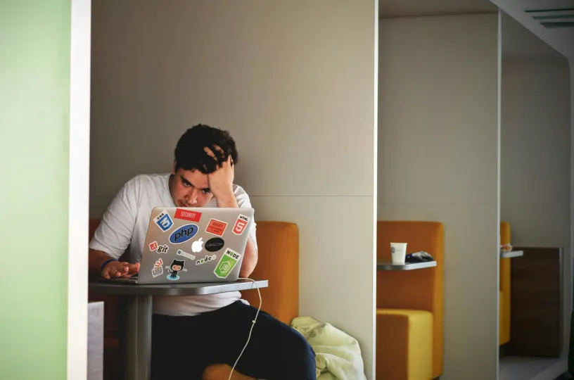 Henkilö työskentelee läppärillä näyttäen stressaantuneelta.