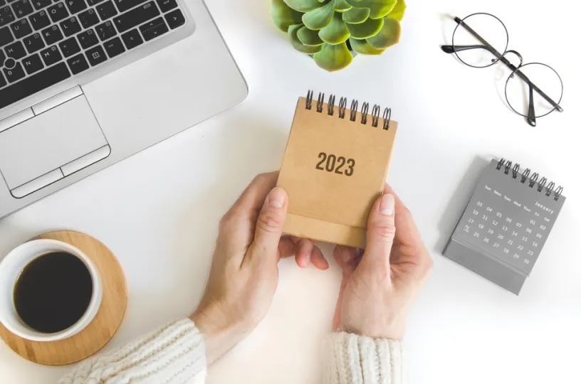 Kuvassa nainen pitää vuoden 2023 kalenteria. 