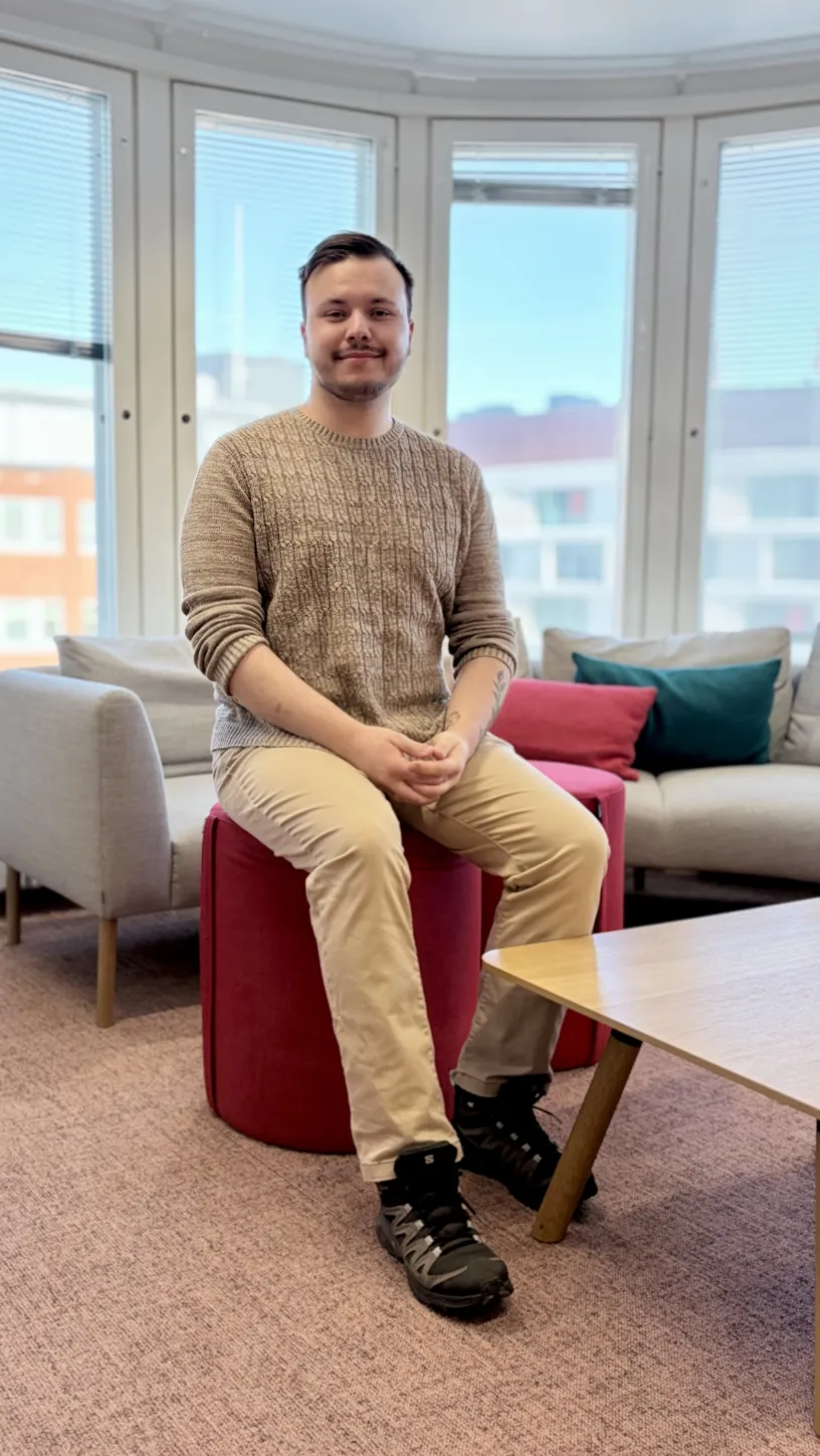 Miro istuu punaisella rahilla olohuoneessa, taustalla isot ikkunat ja sohvia.