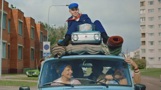 poika istuu neuvostovalmisteisen auton katolla