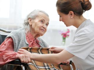 Hoitaja keskustelee iäkkään naisen kanssa. 
