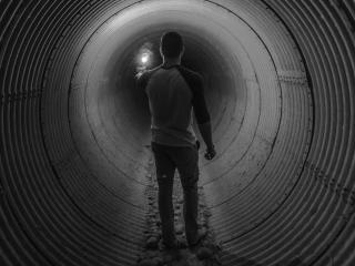Mies kävelee pimeässä tunnelissa eikä näe määränpäätä. 