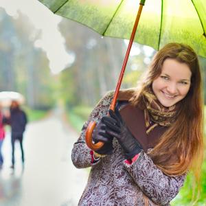 Työttömyyskassa Pron väreissä nainen sateenvarjon alla.
