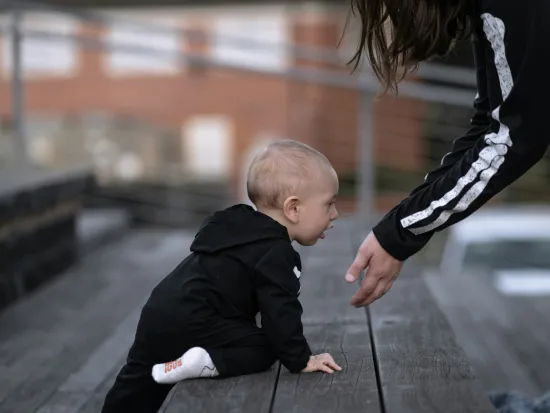 Vaakakuvassa portaita kiipeävä vauva potkupuvussa