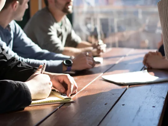 useita henkilöitä istuu pöydän ääressä