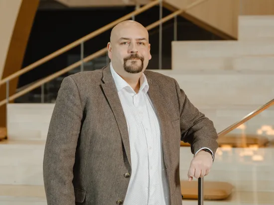 Henrik Haapajärvi seisoo portaikon edessä ruskeassa puvuntakissa ja valkoisessa paidassa.