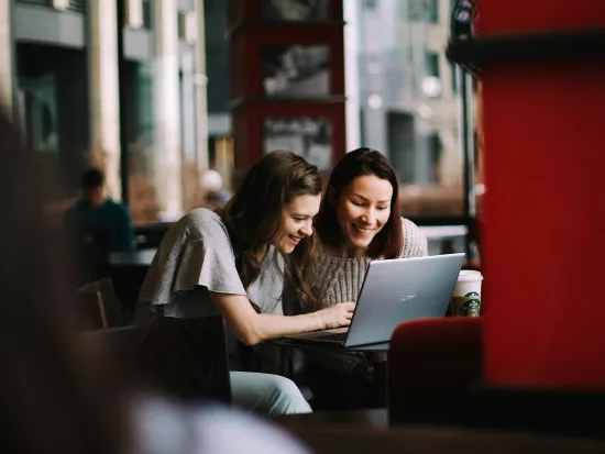 Two people are sitting at a computer.