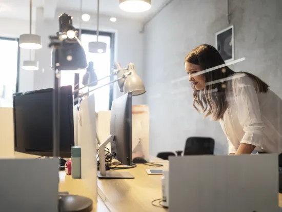 Nainen työskentelee modernissa avotoimistossa tietokoneen äärellä.