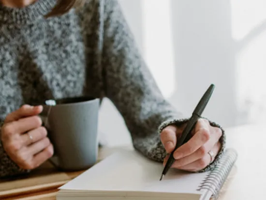 Nainen kirjoittaa vihkoon