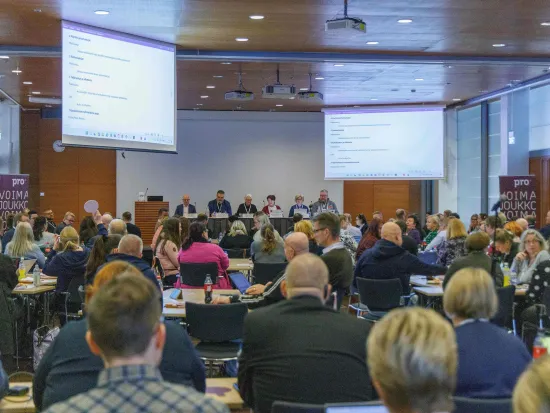 Iso kokoushuone täynnä ihmisiä.