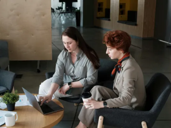 Kaksi ihmistä istuu ja katsoo tietokonetta