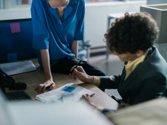 Kaksi henkilöä täyttää paperia