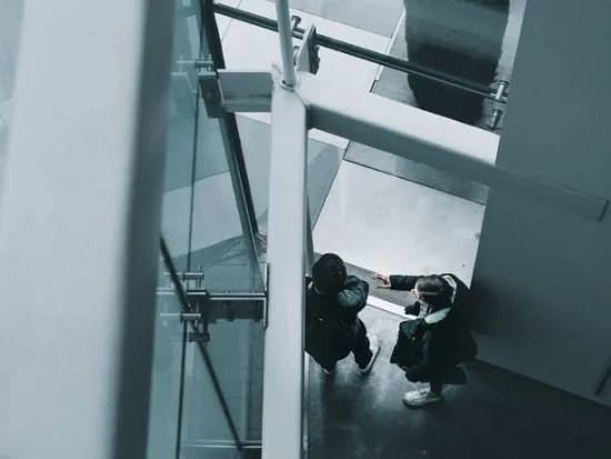 Kaksi ihmistä kättelee modernin rakennuksen sisällä.