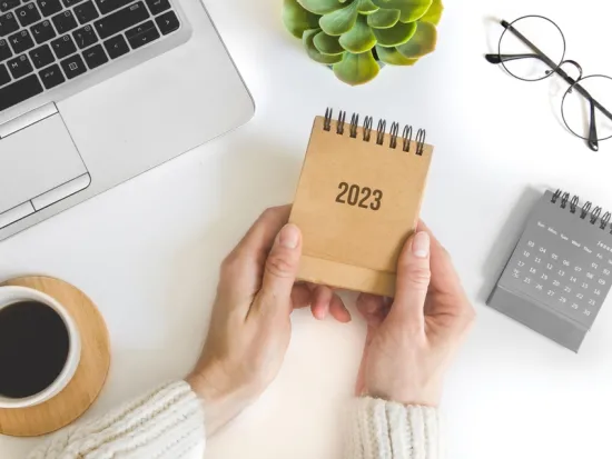 Kuvassa nainen pitää vuoden 2023 kalenteria. 