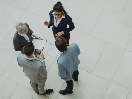 Neljä ihmistä keskustelee virastossa, katsottuna ylhäältä päin.