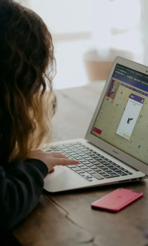 Henkilö käyttää kannettavaa tietokonetta puupöydän ääressä.