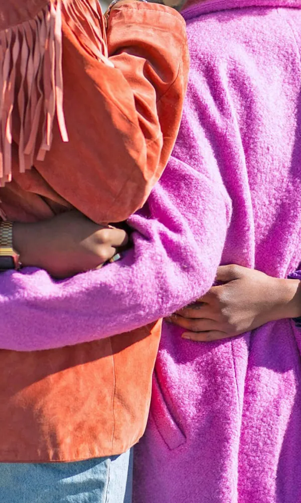 Humane working life is a human right: a picture of people hugging each other showing their backs with bright pink colored jackets