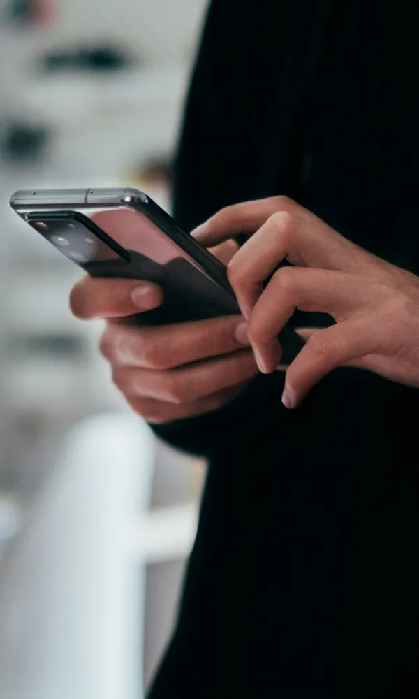 Henkilö käyttää älypuhelinta sisätiloissa.