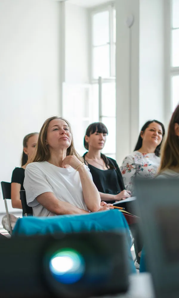henkilöitä istumassa kasvot samaan suuntaan, etualalla kannettavan tietokoneen ruutu